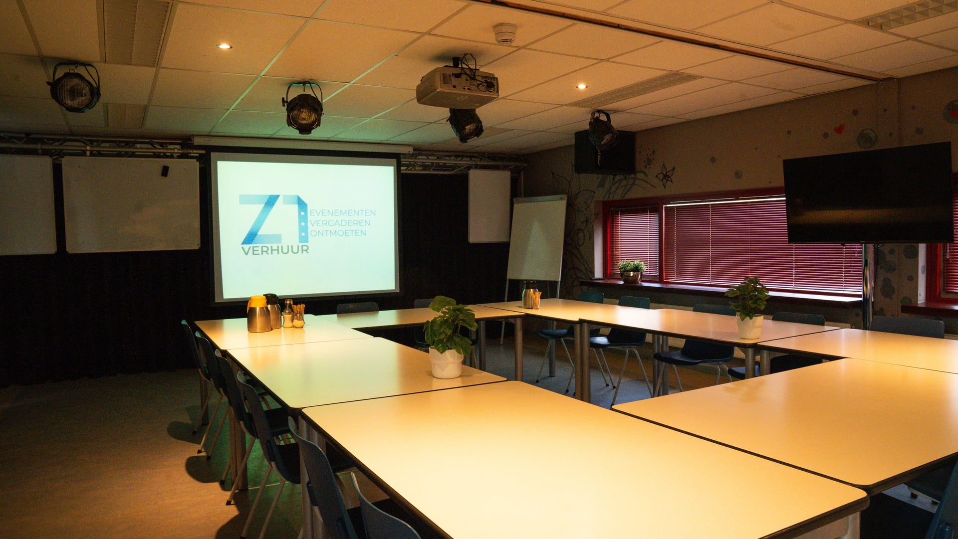 De multifunctionele ruimte in U-opstelling, met projectiescherm, tv-scherm, flipover, whiteboards en koffiekannen op tafel