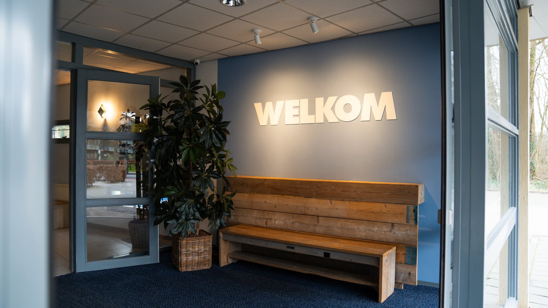 De entree van Z1 Verhuur met verlichte letters WELKOM boven een houten bank